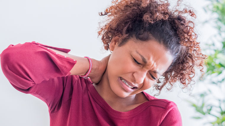 A woman holds her neck in pain from Cervical Degenerative Disc Disease