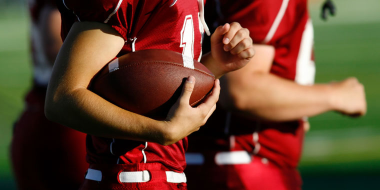 Athlete runs with a football under his arm