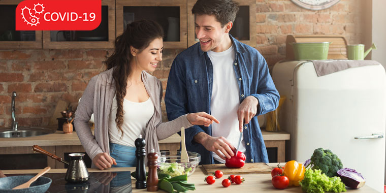 A man and a woman laugh as they prepare a meal together