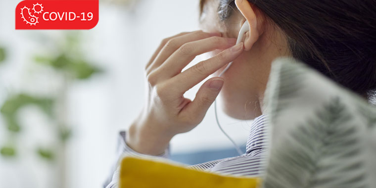 Woman adjusts earbuds in her ear