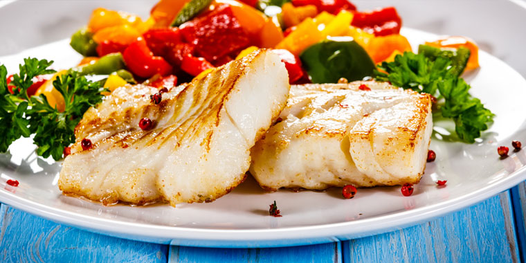 A dinner plate of cooked fish and vegetables