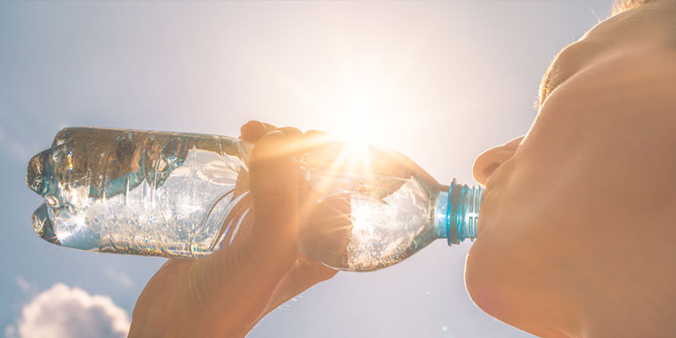 A man drinking a bottle of water during an extreme heat wave.