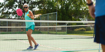 A woman plays pickleball on the court with her paddle in hand