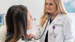 An emergency doctor, wearing a stethoscope, listens to a patient's heartbeat