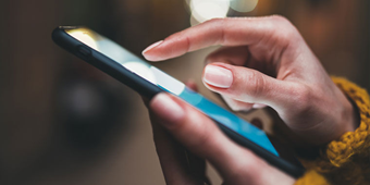 Person holds a smartphone, scrolling through content.