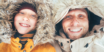 A boy and his father smile in their winter coats in the cold weather