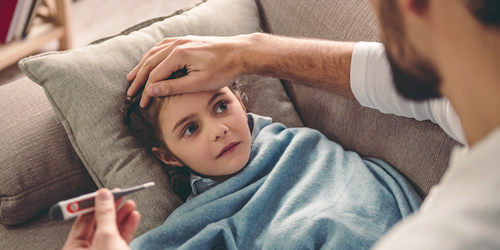 Father caring for a sick child, taking her temperature