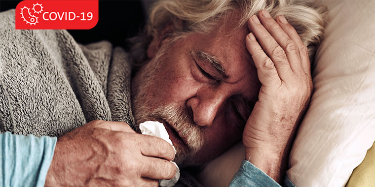 Older gentleman lying on the couch, sick, with a tissue covering his mouth