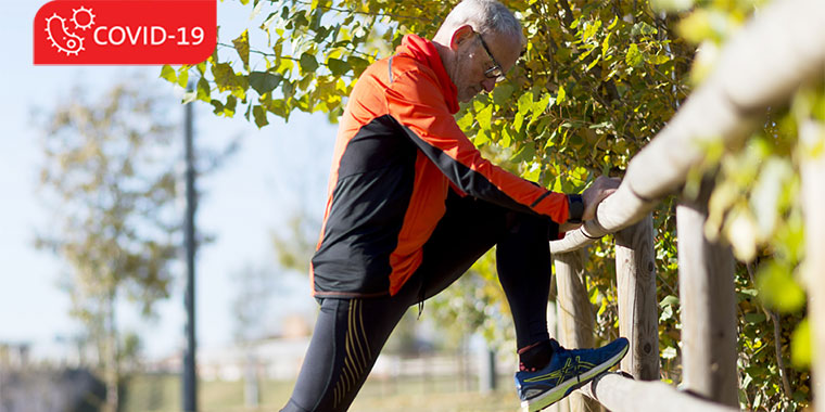 Older male in running clothes, stretching on sidewalk