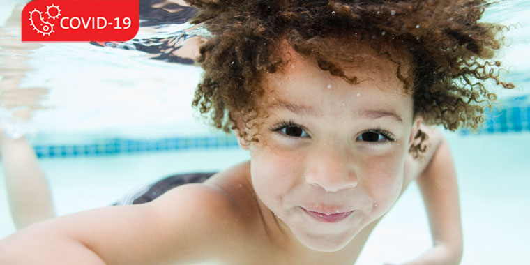 Child swimming, below water, looking at camera