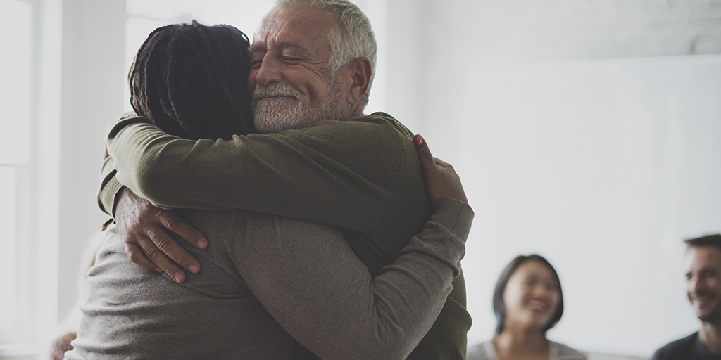 Individuals hugging at a support group meeting