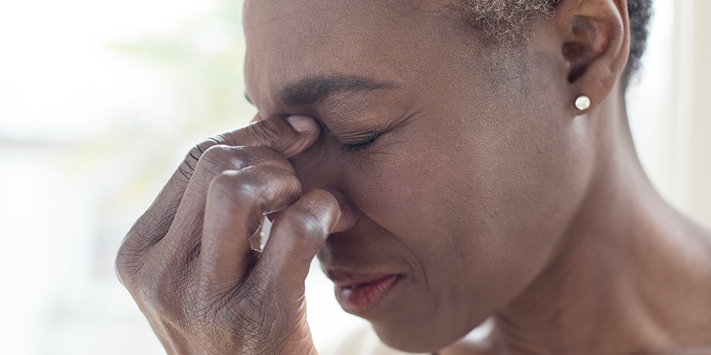 Women wincing in pain, grasping her head