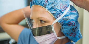 Nurse ties a mask to her face before a c-section
