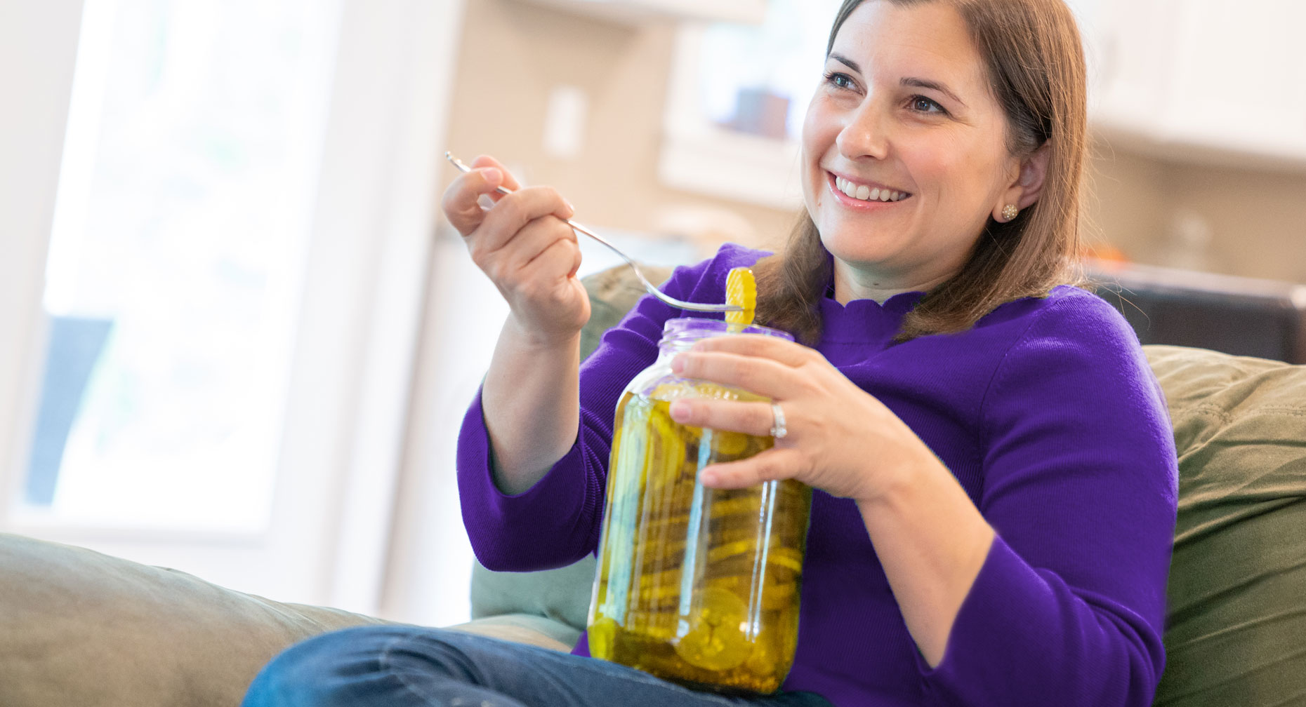 Woman with pregnancy food craving eating on couch