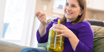 Woman with pregnancy food craving eating on couch